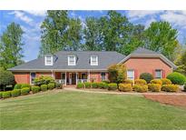 Charming brick home featuring a lush front yard and mature landscaping, creating a welcoming curb appeal at 1015 Brooksglen Dr, Roswell, GA 30075