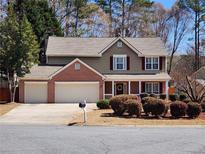 Charming two-story home featuring a three-car garage, landscaped yard, and inviting front porch with decorative wreath at 2702 Brookefield Nw Ln, Kennesaw, GA 30152