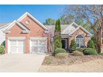 Charming brick home featuring a two-car garage, well-manicured landscaping, and a classic architectural design at 5226 Davis Love Dr, Cumming, GA 30041