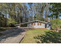 Ranch-style home featuring light brick, flat roofs, and large driveway at 1702 Danrich Dr, Decatur, GA 30032