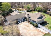 Charming home featuring a stone chimney, light colored siding, and a large concrete driveway at 115 Heritage Cir, Mcdonough, GA 30253