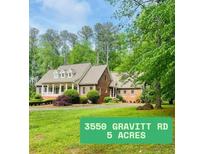 Charming brick home on five acres, featuring a manicured lawn and mature trees at 3550 Gravitt Rd, Cumming, GA 30040