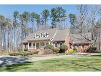 Charming brick home with a welcoming front porch and well-manicured lawn surrounded by mature trees at 3550 Gravitt Rd, Cumming, GA 30040
