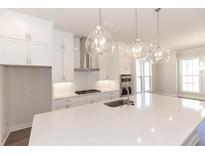 Bright kitchen features an island with pendant lighting, modern appliances, and sleek white cabinetry at 161 Basil St, Cumming, GA 30040