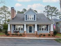 Charming home with a brick chimney, a cozy front porch, and manicured landscaping at 3036 Lassiter Rd, Marietta, GA 30062
