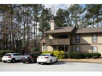 Inviting townhouse with neutral toned paint and front parking nestled among mature trees and landscaping at 401 Woodcliff Dr, Atlanta, GA 30350