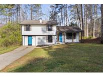 Charming two-story home featuring a manicured lawn and blue doors, nestled amongst mature trees at 3840 Natalie Way, Ellenwood, GA 30294