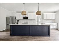 Modern kitchen features a large island, stainless steel appliances, and stylish pendant lighting at 2451 Napa Valley Dr, Villa Rica, GA 30180