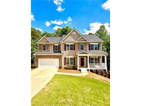 Charming two-story home with a brick and beige exterior, a two-car garage, and a welcoming front porch at 9645 Dunhill Way, Cumming, GA 30028