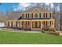 Charming two-story home featuring a welcoming front porch with elegant columns and well-manicured lawn at 215 Morning Glory Rdg, Canton, GA 30115