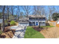 Charming two-story home boasts a blue door, black shutters, and a well-manicured front lawn and driveway at 345 Ivy Mill Ct, Roswell, GA 30076