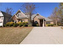 Charming two-story home featuring a well-manicured lawn, brick accents, and a long driveway leading to a welcoming entrance at 1520 Camden Cove Dr, Cumming, GA 30040