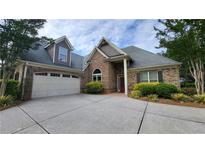 Charming brick home featuring a two-car garage, manicured landscaping, and a welcoming red front door at 1520 Camden Cove Dr, Cumming, GA 30040