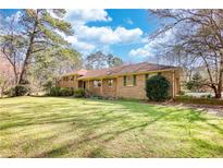 Sprawling ranch-style home with a lush green lawn and mature trees on a sunny day at 5190 Paul Sw Cir, Conyers, GA 30094