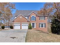 Charming two-story brick home with a two-car garage and a well-manicured front lawn on a sunny day at 1484 Highland Bluff Ct, Suwanee, GA 30024