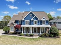 Charming two-story home featuring a welcoming front porch, manicured lawn and a combination of stone and siding at 302 Meadow Lark Xing, Canton, GA 30114