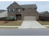 Two-story brick home with a two-car garage and well-manicured front yard on a sunny day at 212 Eleanora Way, Loganville, GA 30052
