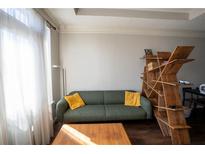 Modern living room with a sleek green sofa, bright window, and an interesting wooden shelf at 401 16Th Nw St # 1463, Atlanta, GA 30363