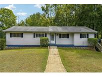 Charming single-story home with a well-manicured lawn, complemented by mature trees and lush greenery at 2415 Wales Dr, Austell, GA 30106