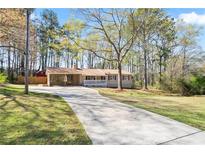 Charming single-story home with a long driveway and a covered porch, nestled among mature trees on a sunny day at 5095 Derry Nw Rd, Acworth, GA 30101