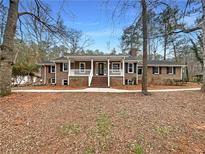 Charming brick home featuring a welcoming front porch, mature trees and landscaping at 121 Northwoods Rd, Sharpsburg, GA 30277