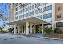 Exterior view of the building entrance featuring a covered driveway, stone columns, and glass doors at 215 Piedmont Ne Ave # 2205, Atlanta, GA 30308