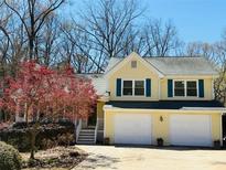 Charming yellow two-story home with a two-car garage, blue shutters, and a well-maintained front yard at 45 Somerset Ct, Covington, GA 30016