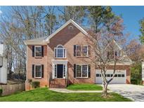 Charming two-story brick home with black shutters, green lawn, and attached two car garage at 4271 Weston Sw Dr, Lilburn, GA 30047