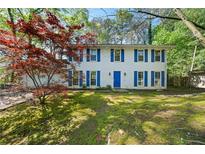 Charming two-story home with blue shutters and a well-maintained front yard surrounded by mature trees at 985 Lake Haven Ct, Roswell, GA 30076