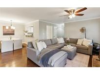 Open-concept living room boasts hardwood floors, a ceiling fan, and a comfortable gray sectional sofa at 2901 Lenox Rd # 1002, Atlanta, GA 30324