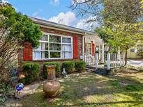 Charming brick home featuring a quaint front yard with mature landscaping and red window shutters at 46 W Belle Isle Rd, Atlanta, GA 30342