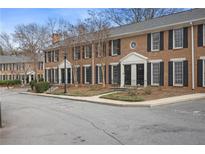 A brick townhouse with black shutters, trimmed windows, and well manicured landscaping at 1101 Collier Nw Rd # V3, Atlanta, GA 30318