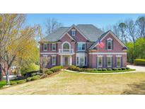 Beautiful brick home featuring a well-manicured lawn, an American flag, and mature trees at 4073 Hickory Fairway Dr, Woodstock, GA 30188