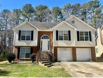 Split level home with a brick and siding exterior, a two-car garage, and mature trees at 2695 Lindsey Oak Ln, Lawrenceville, GA 30044