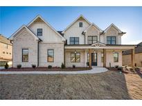 Striking two-story home boasts a brick facade, inviting porch, and well-manicured lawn at 4281 Sierra Creek Ct, Hoschton, GA 30548