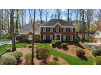 Two story brick home boasts a landscaped front yard and mature trees at 4340 Sprucebough Dr, Marietta, GA 30062