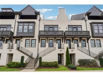 Charming townhome with a painted brick facade, black trim, and inviting staircases leading to covered entryways at 6682 Sterling Dr, Atlanta, GA 30328