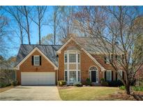 Charming two-story brick home featuring a manicured lawn and attached two-car garage at 210 Chiswick Close, Johns Creek, GA 30022