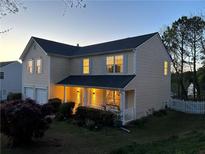 Charming two-story home with a covered front porch, well-manicured lawn, and inviting curb appeal at dusk at 1002 River Plantation Drive, Woodstock, GA 30188