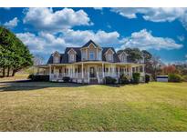 Charming two-story home with a spacious porch and well-manicured lawn under a blue sky at 2002 Orchard Terrace, Loganville, GA 30052