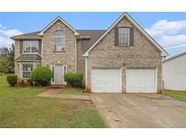 Traditional two-story brick home featuring an attached two-car garage, arched window, and manicured landscaping at 5080 Galleon Xing, Decatur, GA 30035