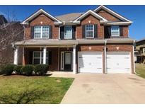 Two story brick home with an attached two car garage and manicured lawn at 6645 Oak Hill Pass, Fairburn, GA 30213