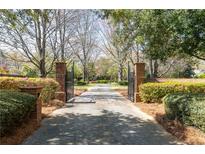 Gated driveway entrance with brick pillars, lush landscaping, and mature trees leads to the estate at 3847 Sweet Bottom Dr, Duluth, GA 30096