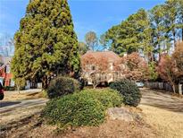 Charming home exterior featuring mature trees, lush landscaping, and a well-maintained lawn at 3655 Brisbane Dr, Marietta, GA 30062