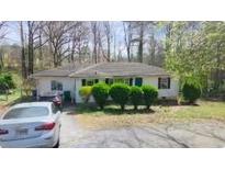 Charming single story home with a driveway and green shrubs in front of the house at 5077 Redan Rd, Stone Mountain, GA 30088