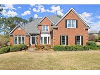Charming two-story brick home with manicured lawn and mature landscaping in a desirable neighborhood at 13090 Magnolia Crescent Dr, Roswell, GA 30075