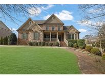 Charming two-story home with brick and stone facade, inviting front porch, and a lush green lawn at 7740 Nesbit Ferry Rd, Atlanta, GA 30350