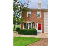 Charming brick townhouse featuring a well-manicured lawn and vibrant red front door at 988 Old Holcomb Bridge Rd, Roswell, GA 30076