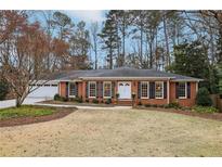 Charming brick home featuring a well-manicured lawn and black shutters with green landscaping at 185 W Spalding Dr, Sandy Springs, GA 30328
