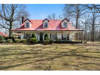 Charming home features a red roof, dormer windows, and a welcoming front porch surrounded by mature landscaping at 680 Milligan Creek Rd, Roopville, GA 30170